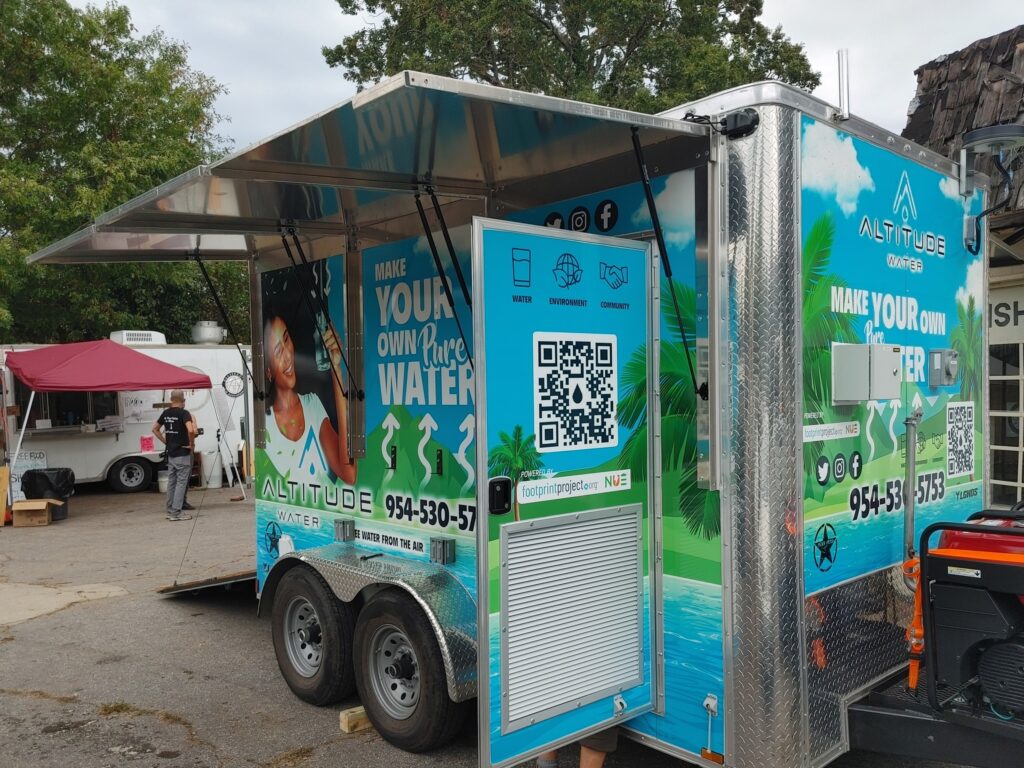 Altitude Water mobile atmospheric water generator trailer at a community event, producing clean drinking water from air with branded outreach display.