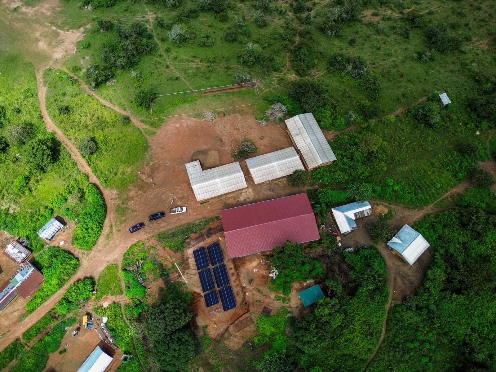 Altitude Water off-grid atmospheric water generator installation with solar panels in rural community, supporting sustainable clean drinking water solutions.
